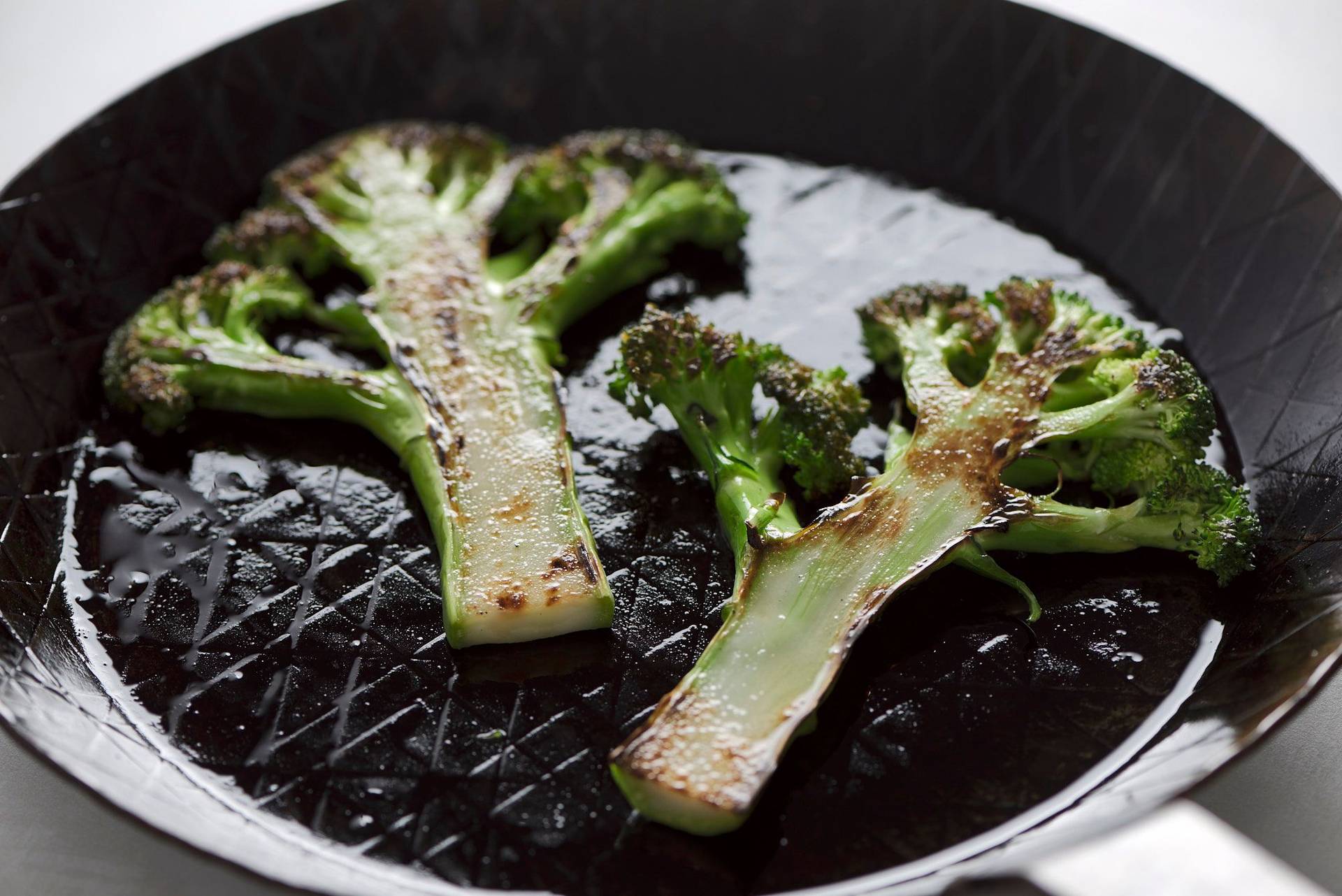 roasted broccoli in a cast iron pan on a white sapienstone top