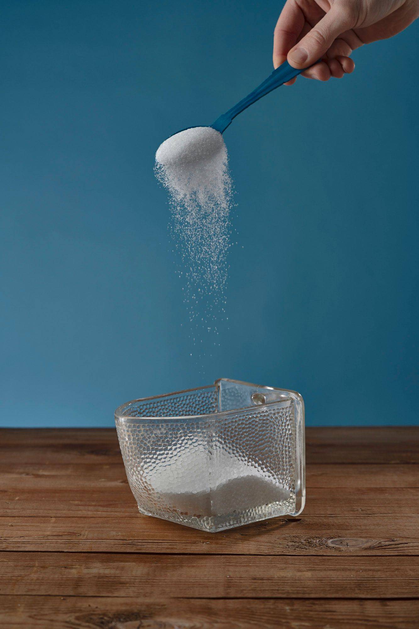 sugar sugar in a vintage jar on a wooden table with blue background