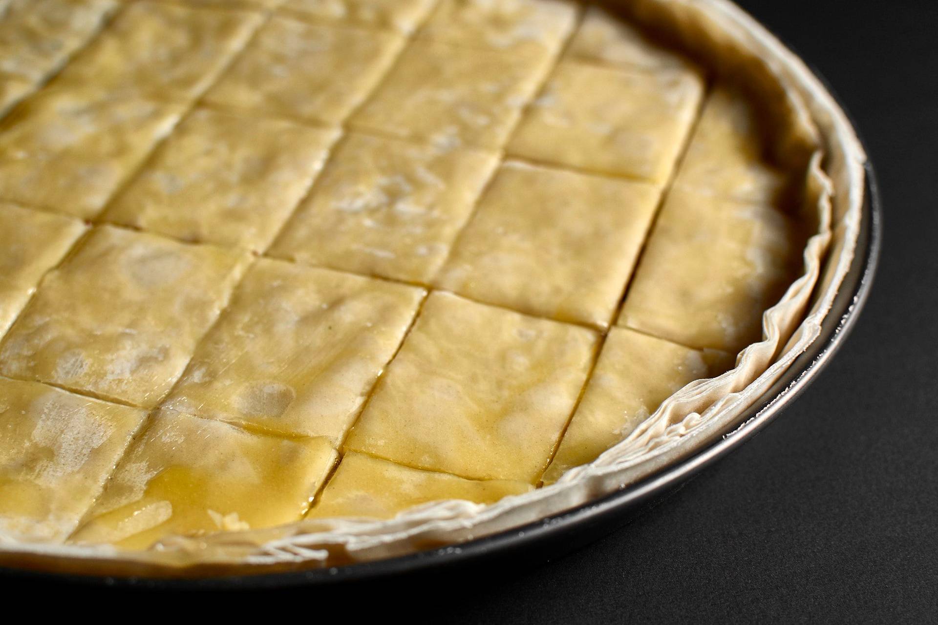 herstellung von baklava mit haselnüssen und walnüssen in einer backform auf schwarzem hintergrund