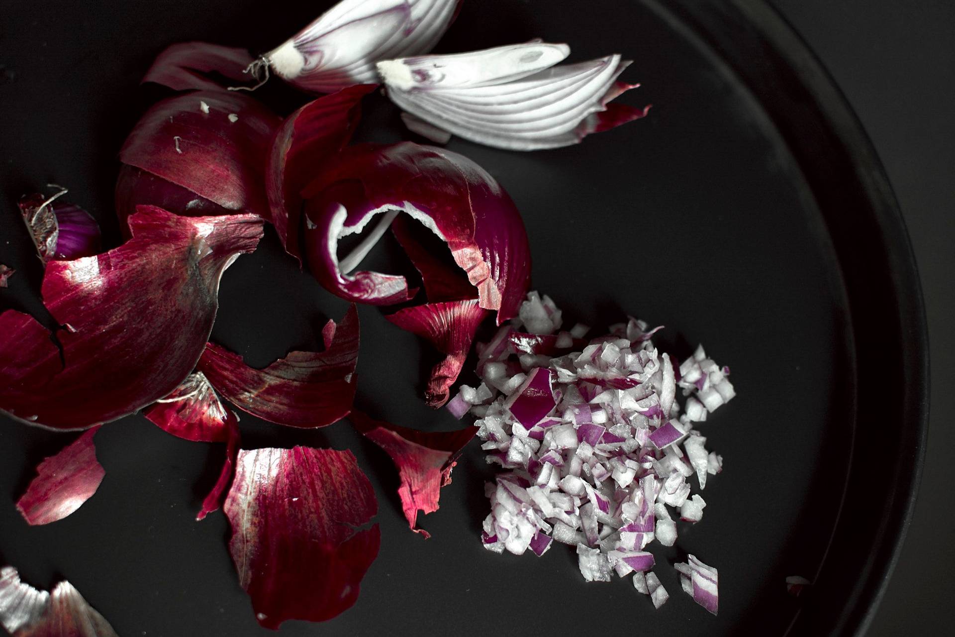 red onions in a baking pan on black background