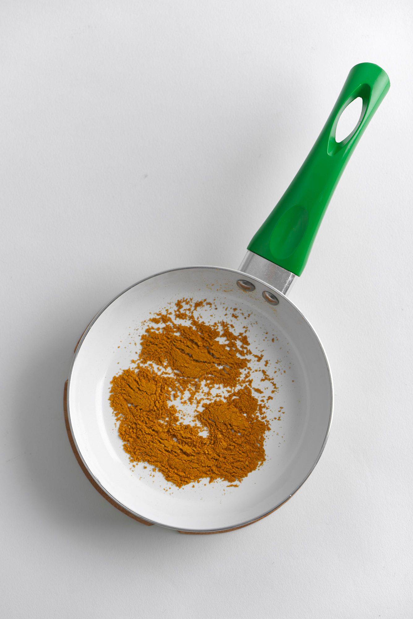 roasted madras curry powder in a green pan on a gray plate with white background