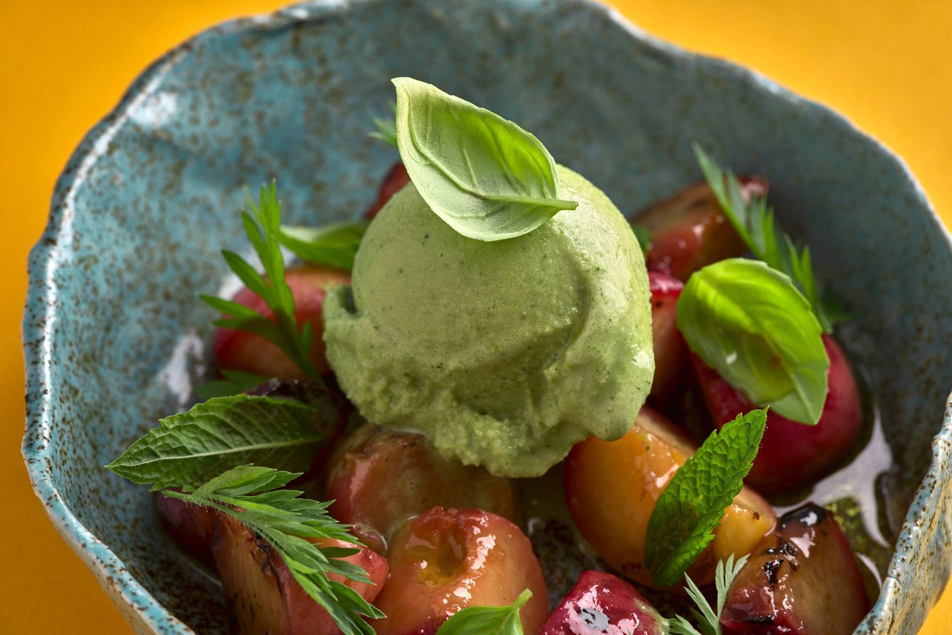 herbs-and-yogurt-ice-cream-with-grilled-peaches-and-greek-olive-oil herbs and yogurt ice cream with grilled peaches and greek olive oil in a turquoise ceramic bowl with yellow background