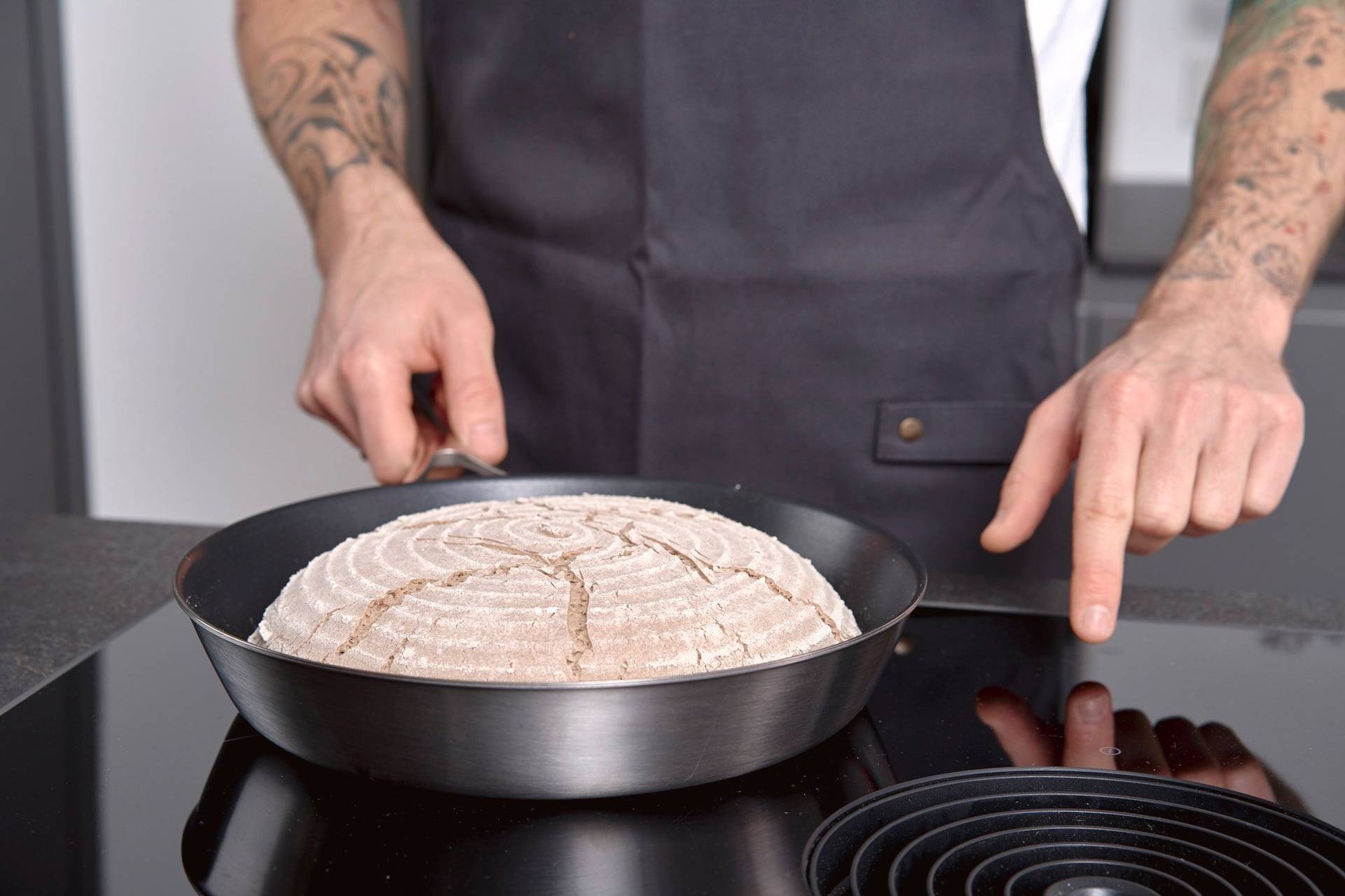 man heating up a pan with rye sourdough bread before baking in home kitchen