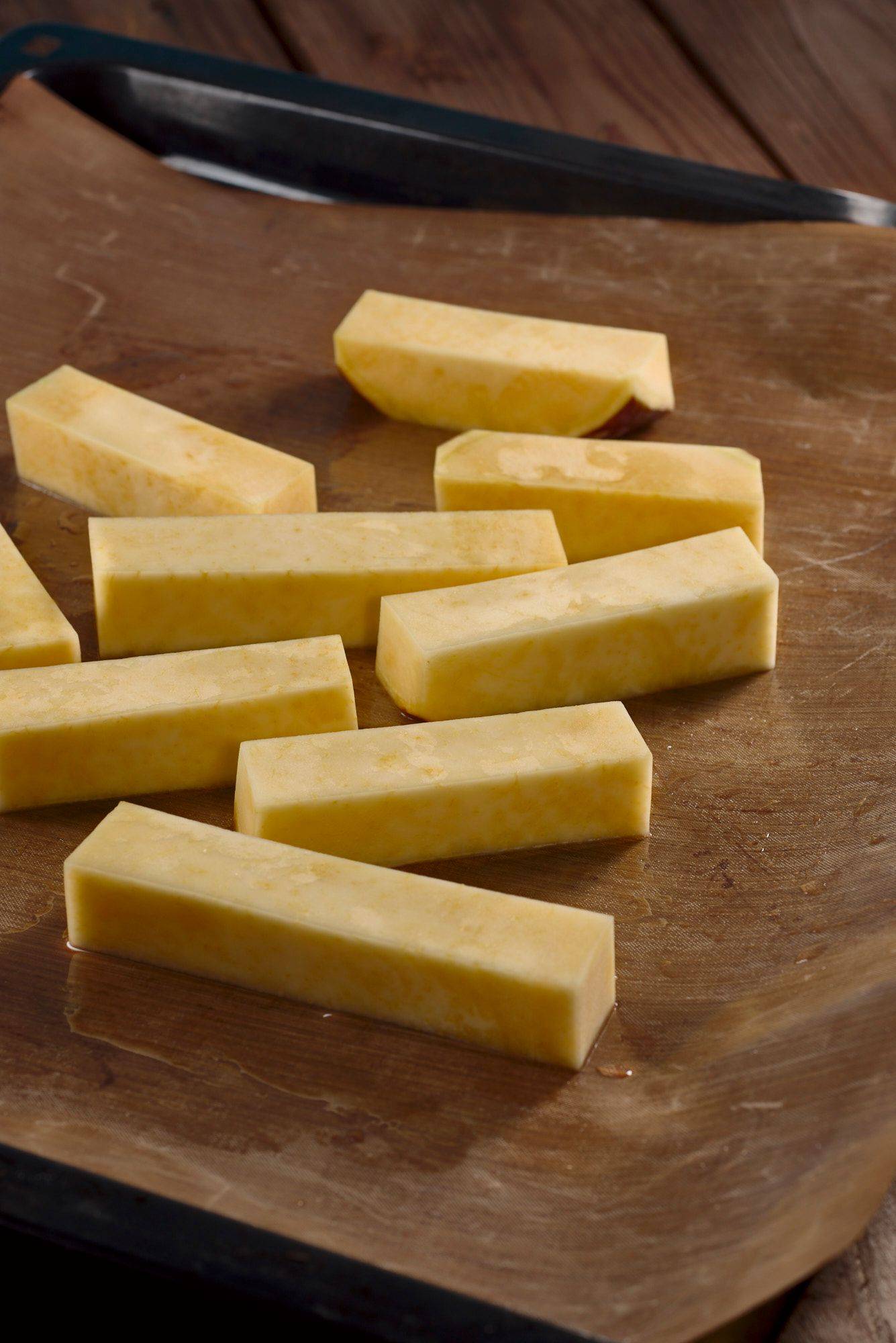 rutabaga sticks on a baking sheet with wooden table