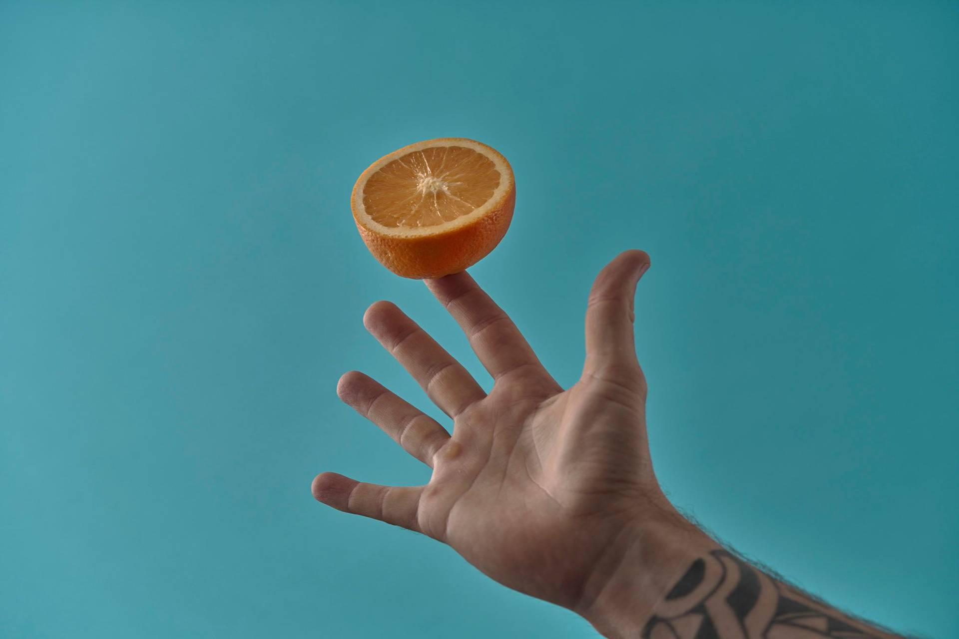 hand holding an orange on blue background