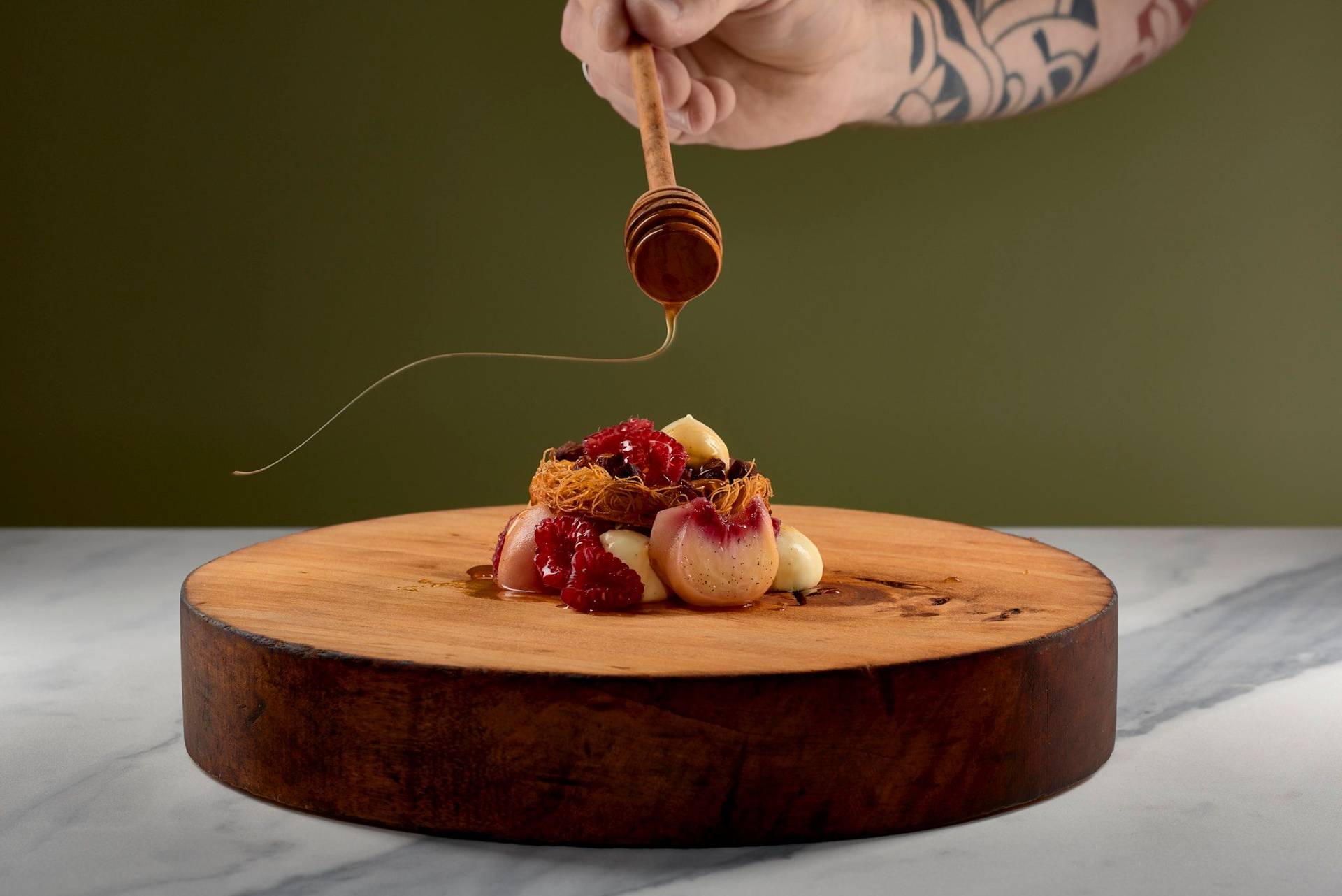 peach melba dessert on a wooden plate with a marbled sapienstone top and green background