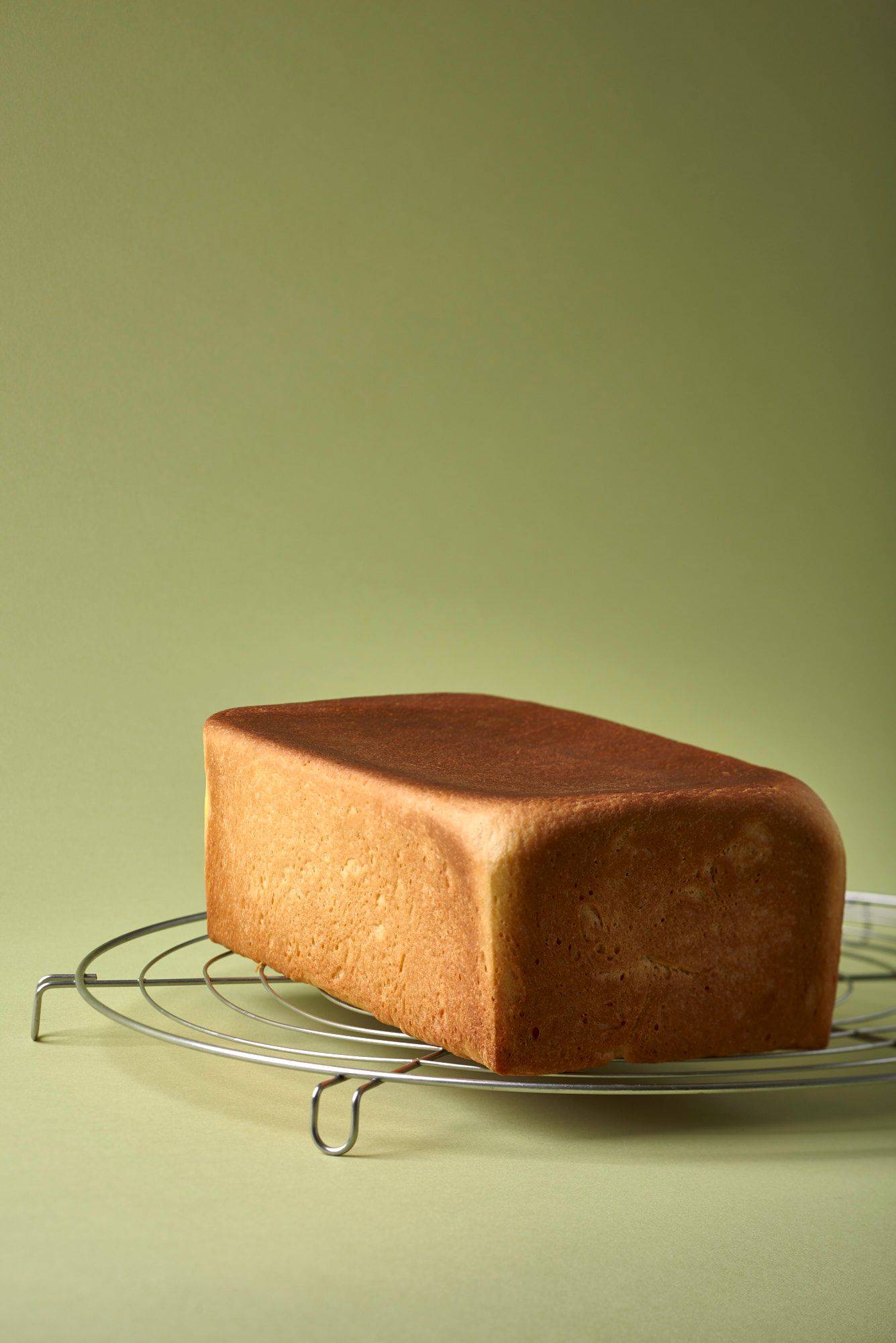 a loaf of brioche on a baking grid with green background