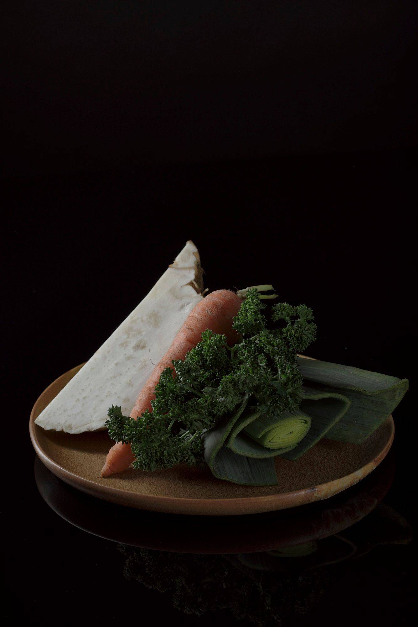 greens on a brown ceramic plate with black background