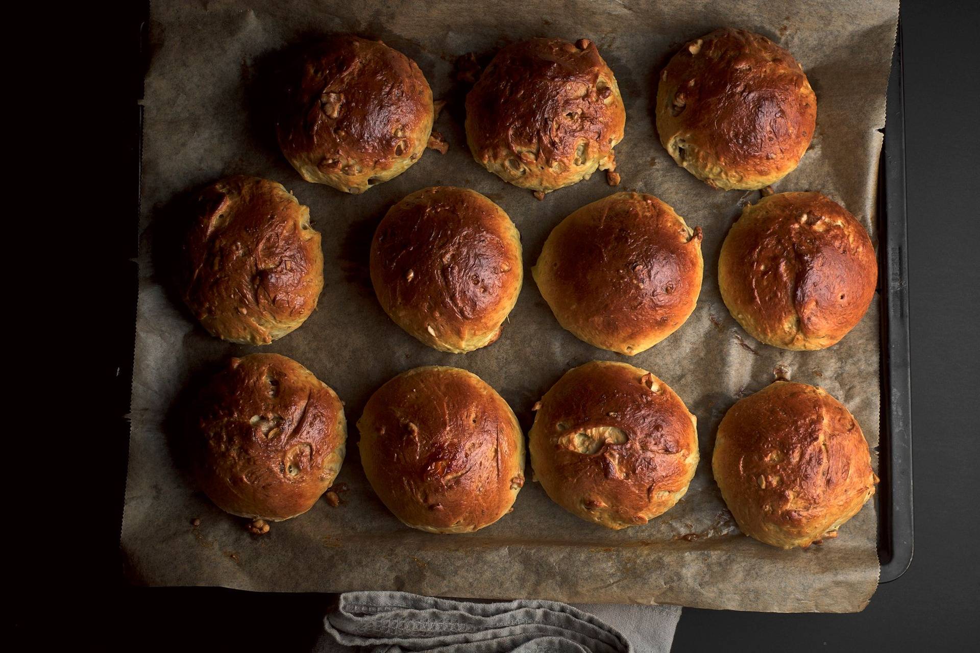 brioche buns with walnuts on a baking sheet with black backgound