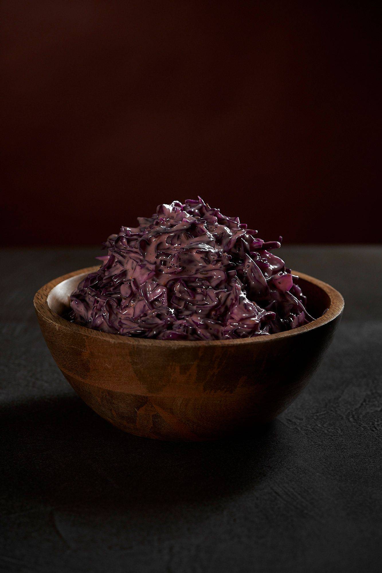 red cabbage coleslaw in a wooden bowl with brown background