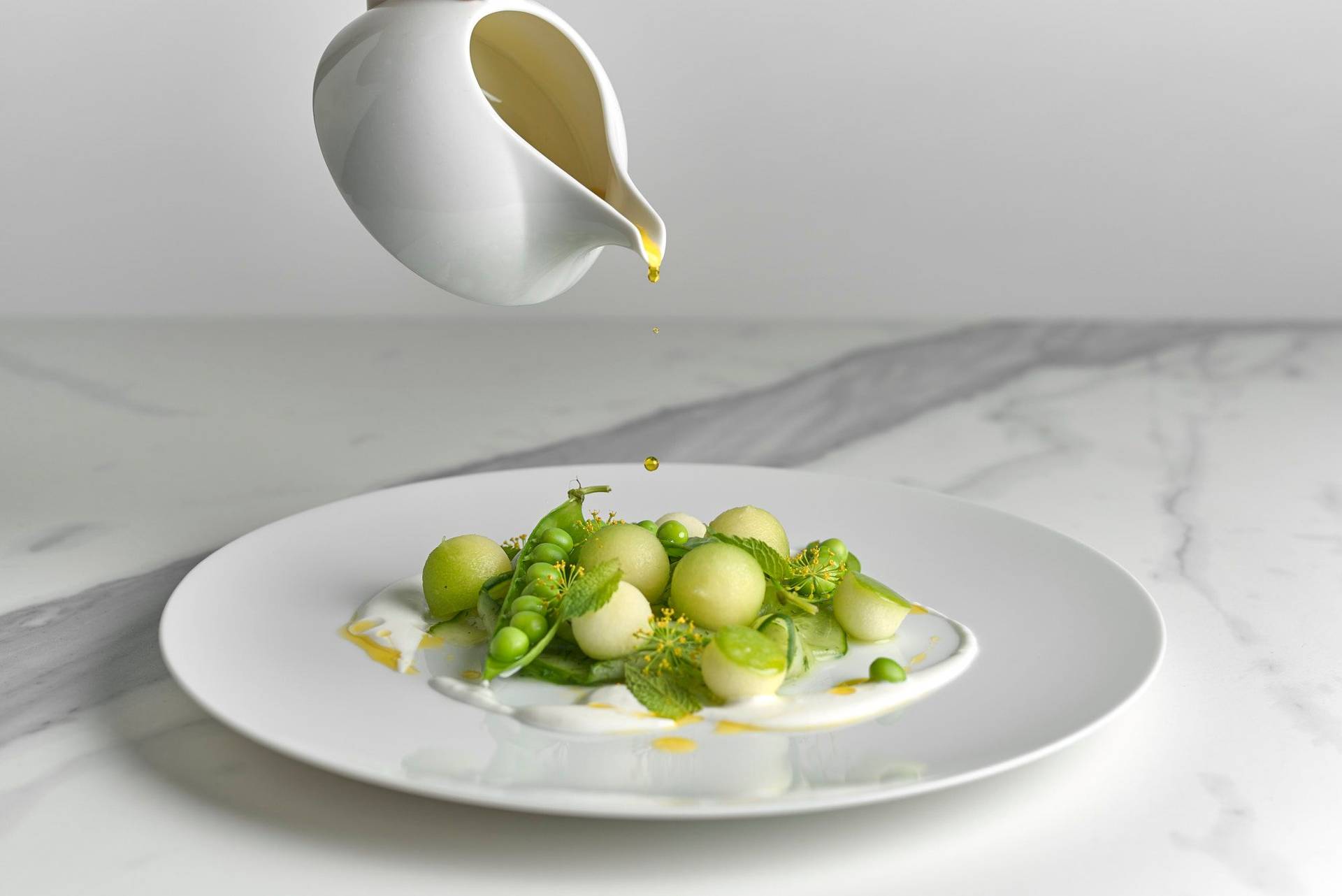 fruchtiger gurkensalat mit melone und leinöl auf einem weißen teller mit marmoriertem sapienstone top