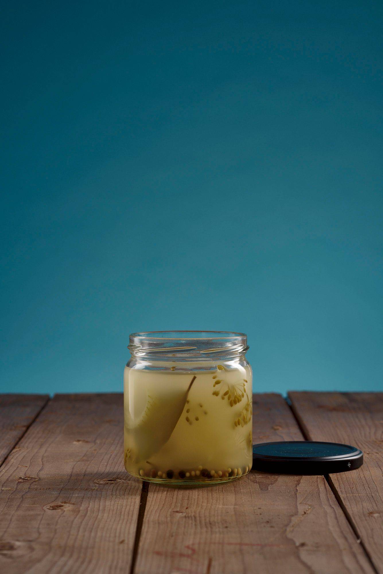 a glass of gherkin pickles stock with wooden table and blue background