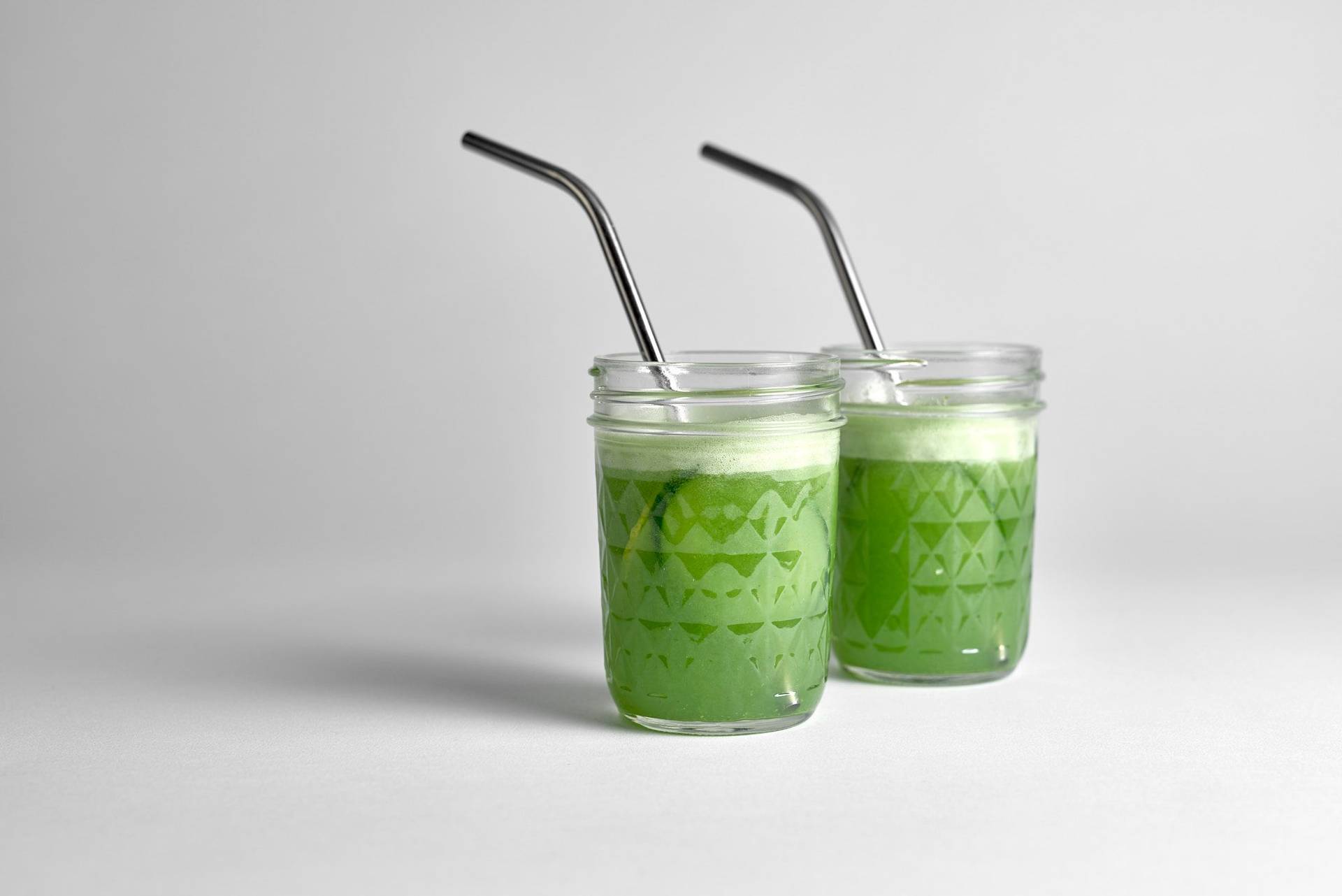 two glasses of cucumber daiquiri cocktail with metal straws on white background