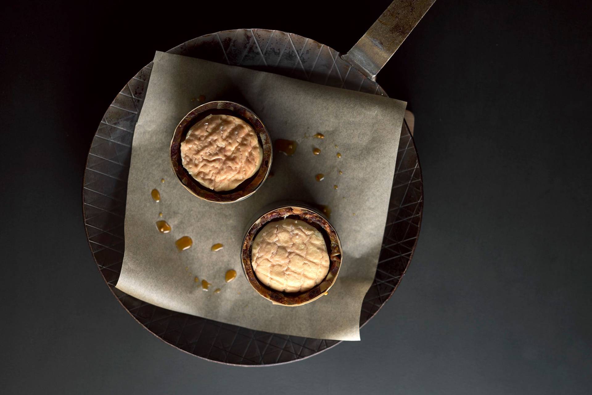 two kale cakes in a cast iron pan on black background