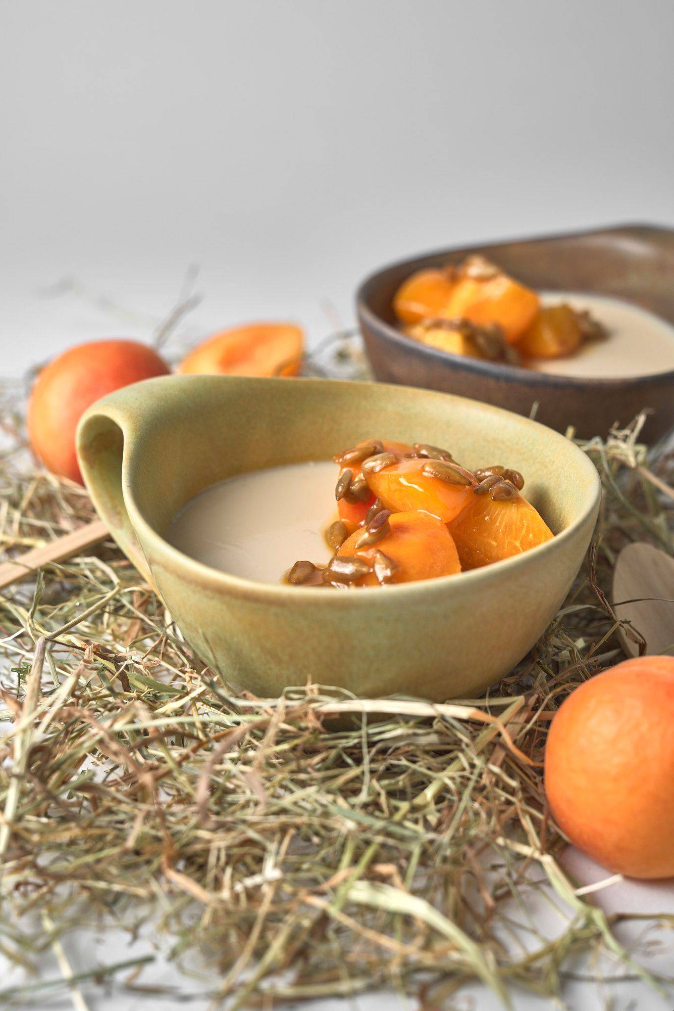 hay panna cotta with caramelized apricots and sunflower seeds on white background