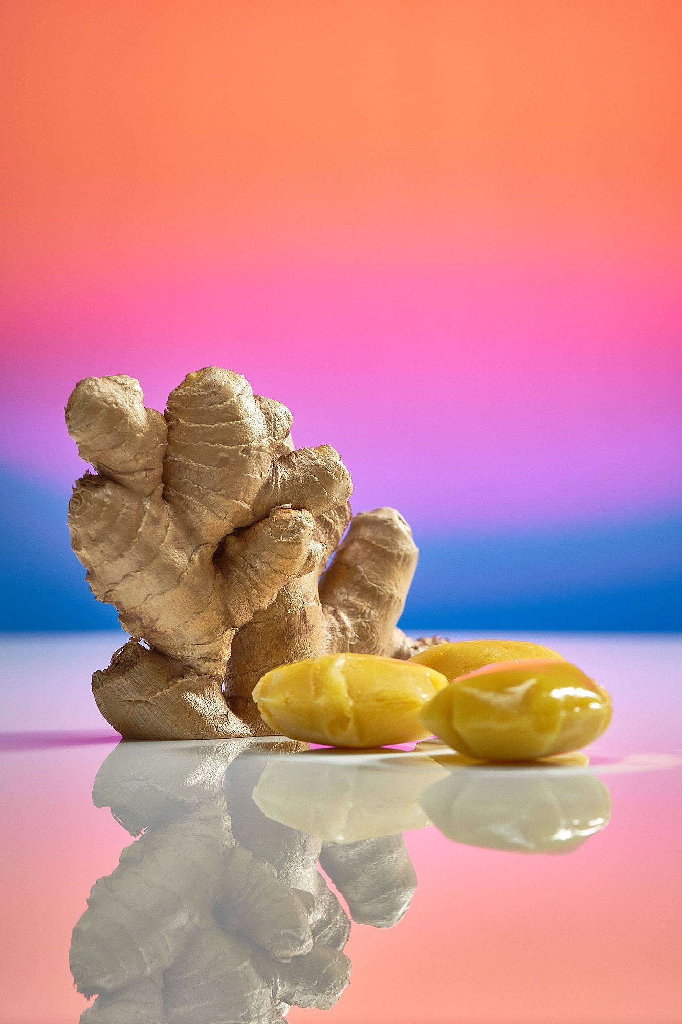 fresh ginger and ginger ice cubes on rainbow colored background