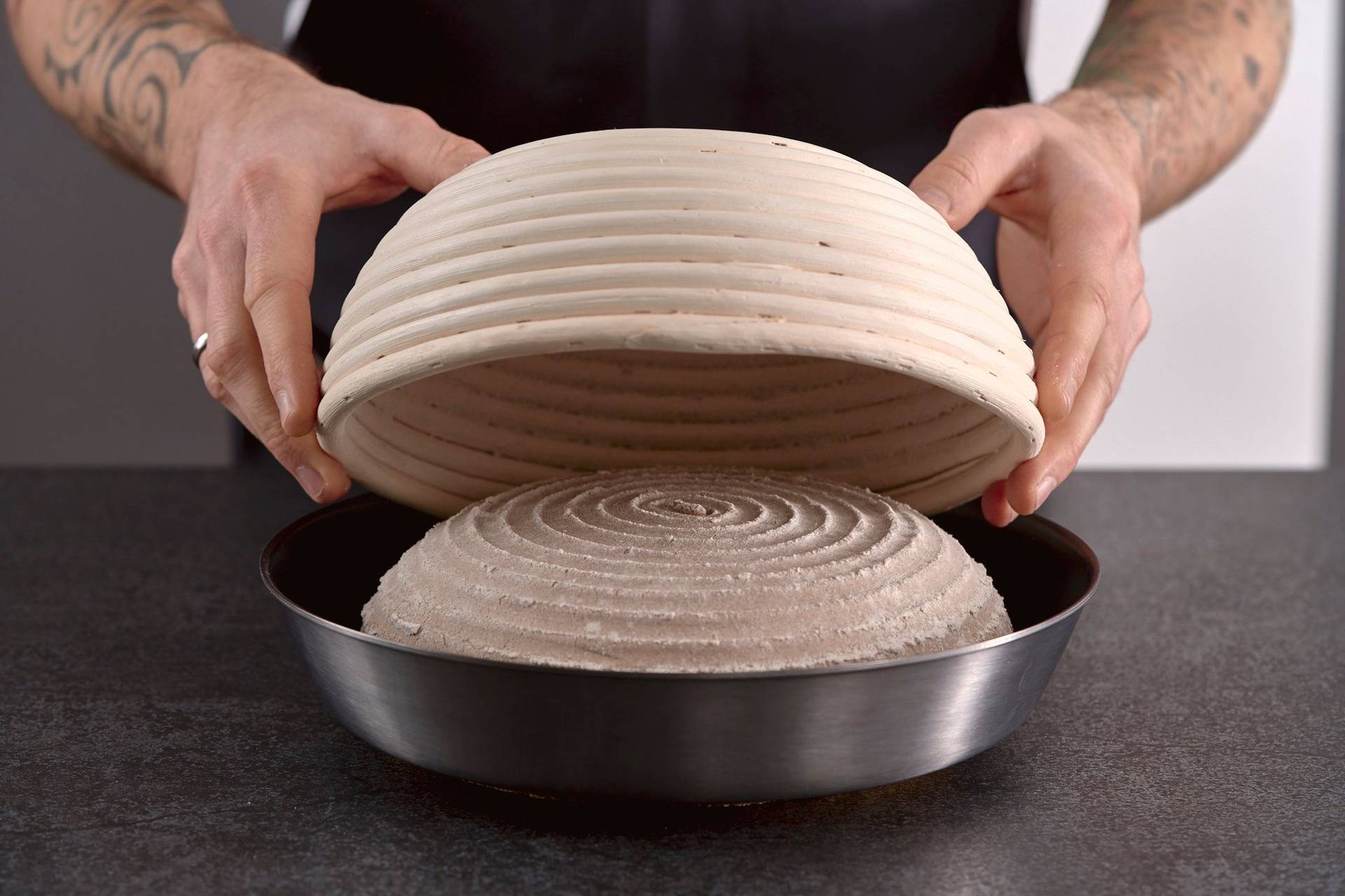 man turning over proofed rye sourdough bread into a pan in home kitchen