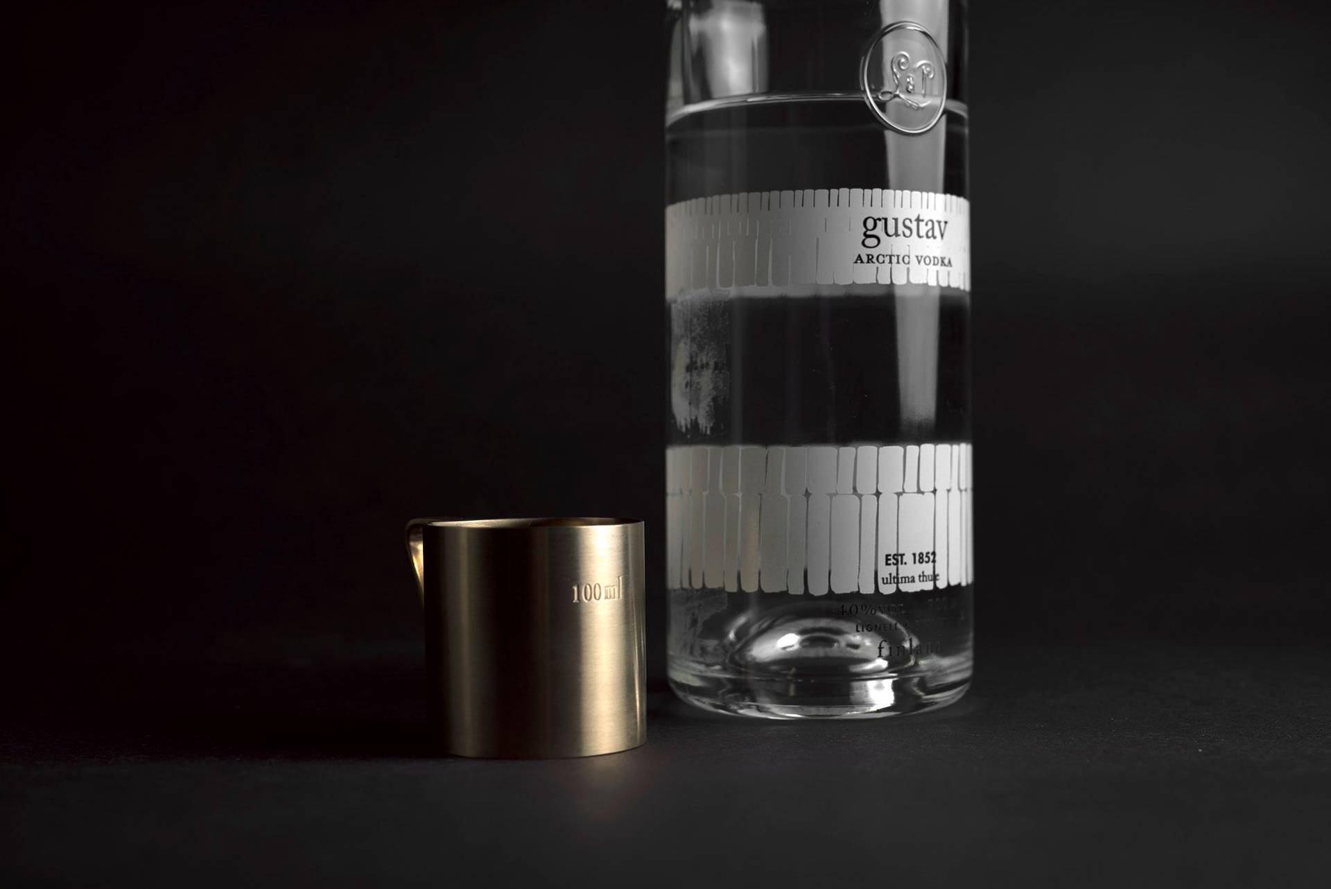 gustav vodka with brass measuring cup on black background