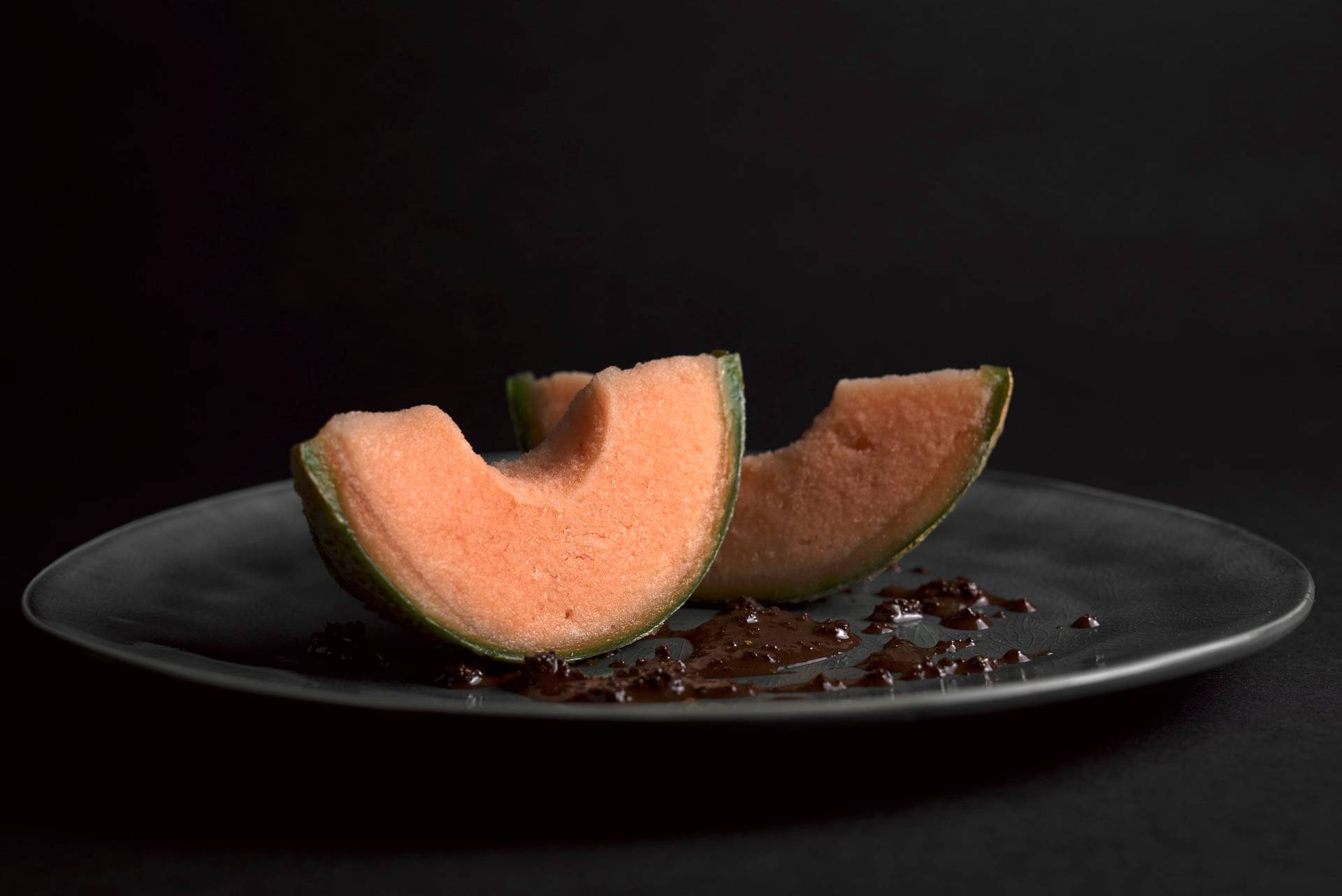 cantaloupe melon sorbet with spicy chocolate pesto on a gray plate with black background
