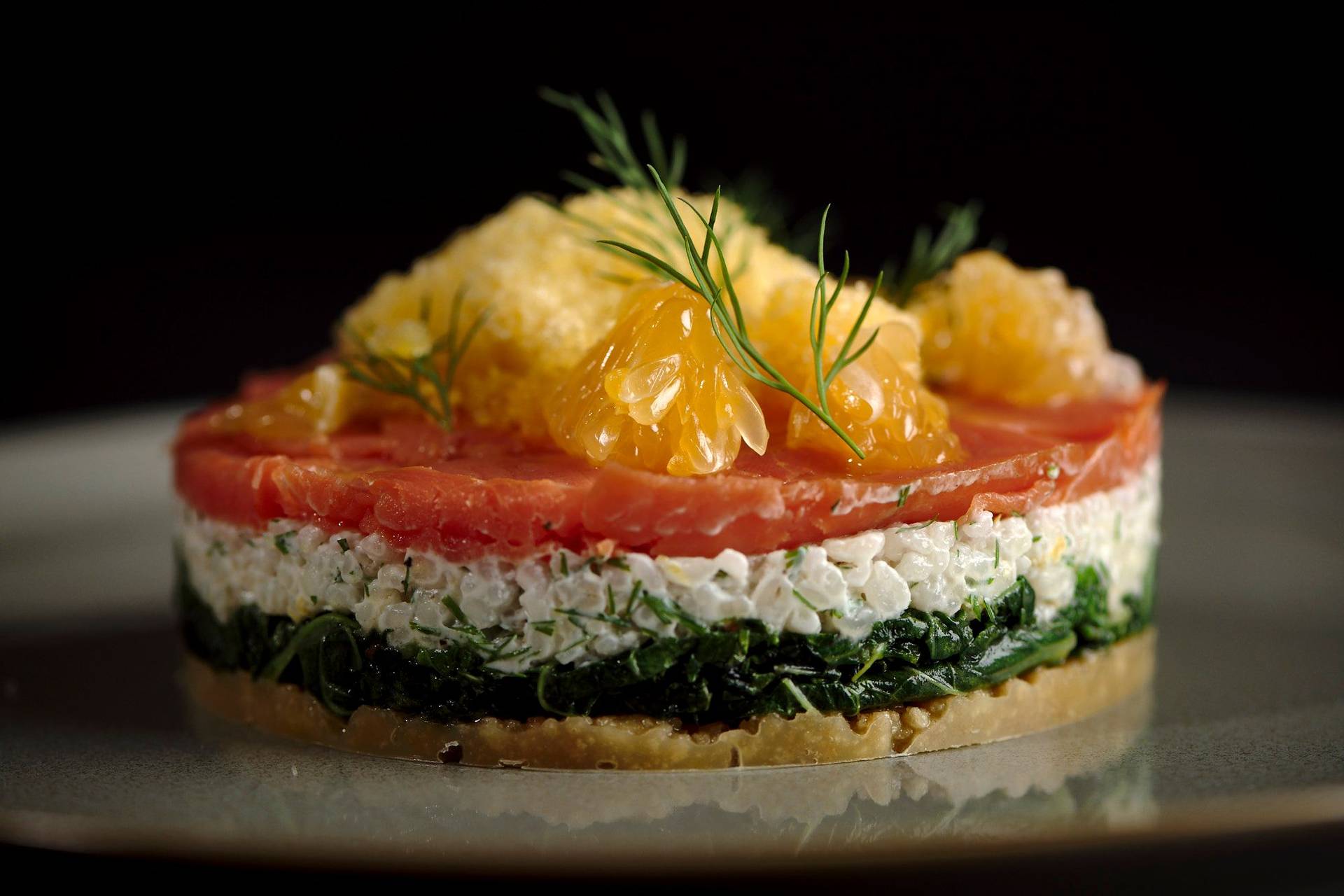 cured salmon tart with tangerine granita on a gray plate with black background