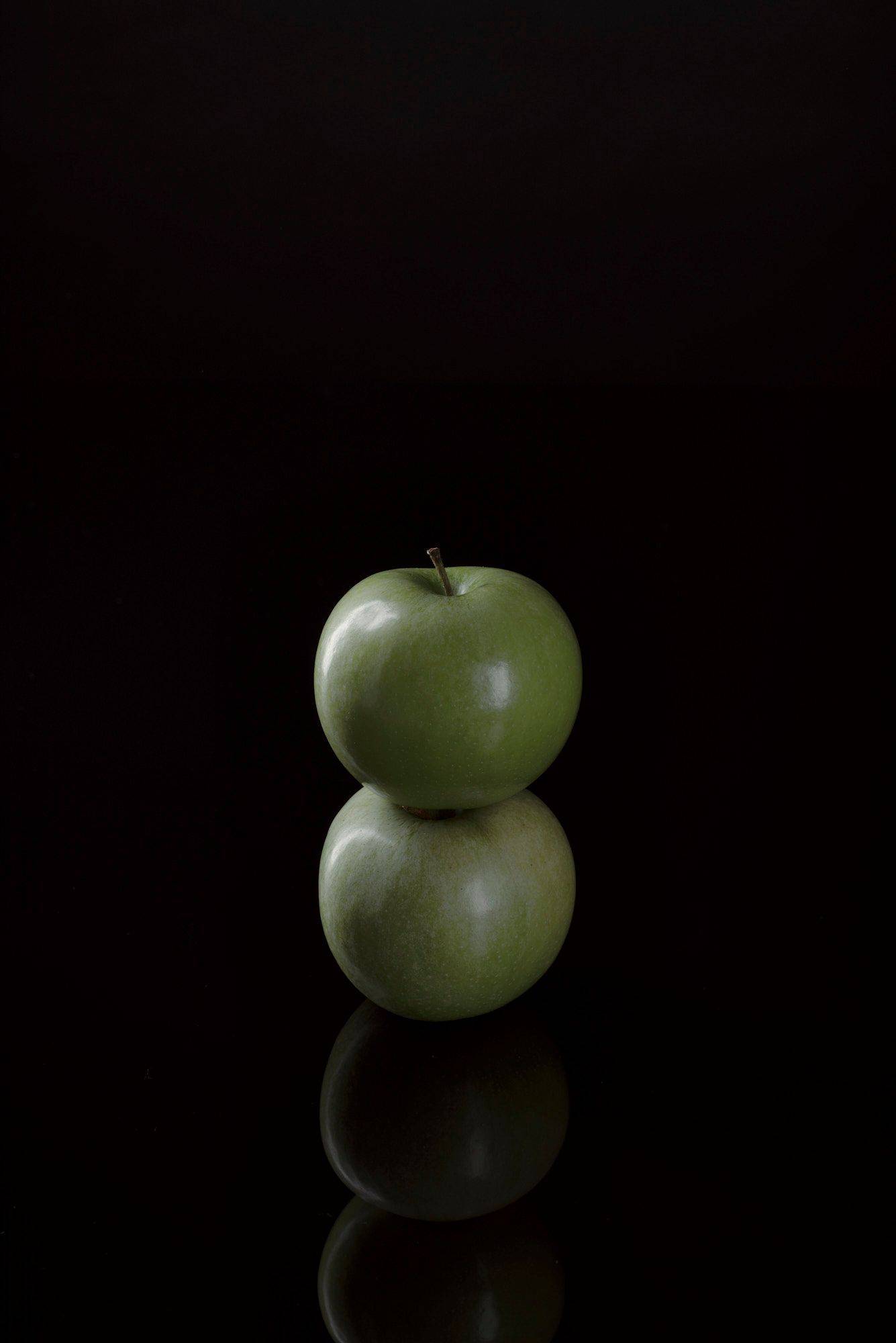 zwei grüne äpfel mit schwarzem hintergrund