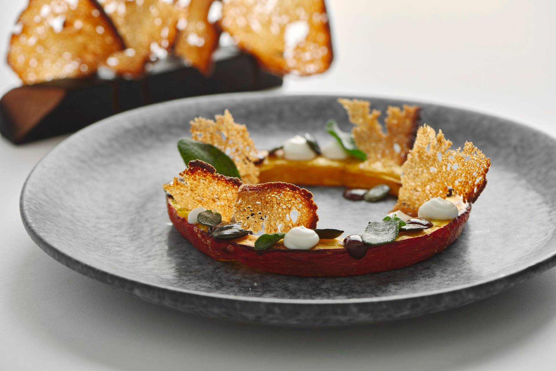 pumpkin variation with sage and sourdough bread on a gray plate with white background